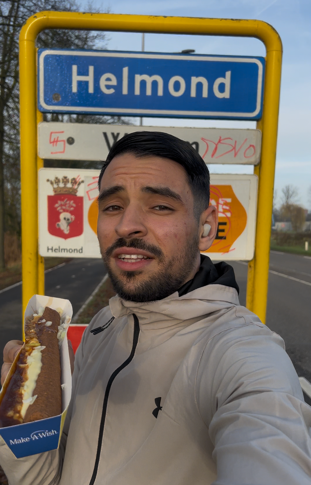 Appie met een frikandel speciaal bij het plaatsnaambord van Helmond